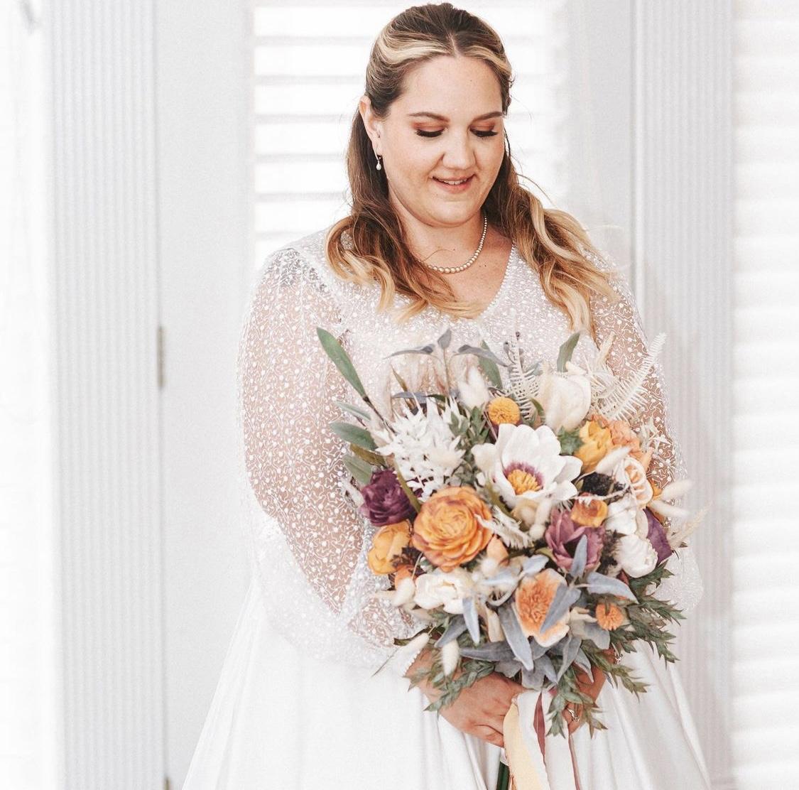 a beautiful bride in her modest wedding gown while holding a bouquet of flowers