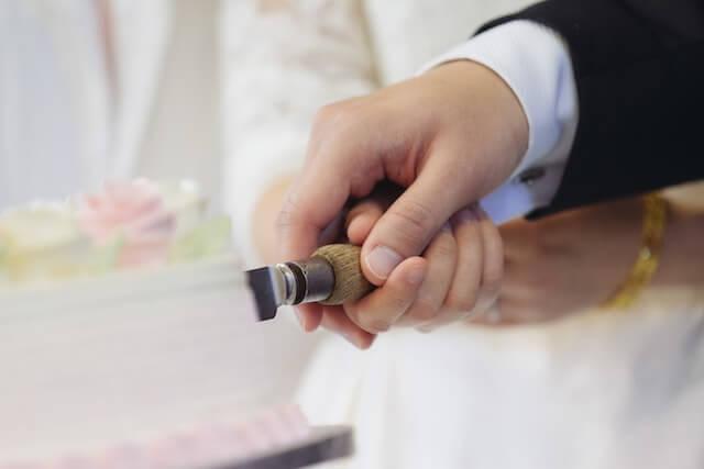 a close-up shot of a couple's hand cutting their cake during the wedding