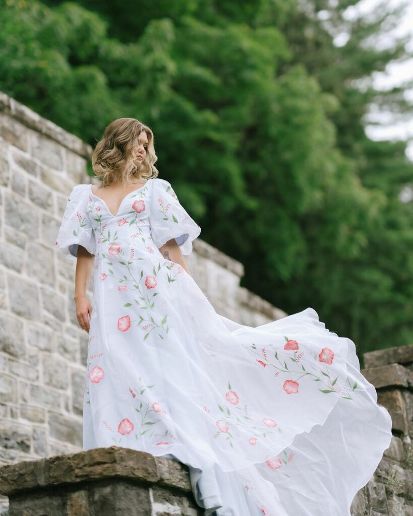 a woman wearing a hand painted, floral dress