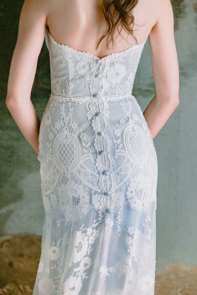 the back details of a blue, fitted wedding dress