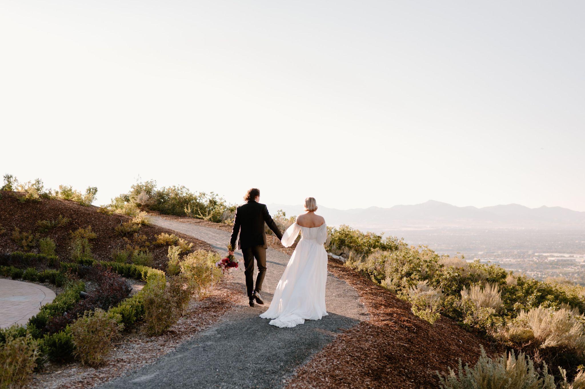 bride and groom walking on a trail overlooking the city